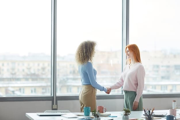 Two professionals in a bright office, shaking hands after a successful negotiation. Documents are on the table.