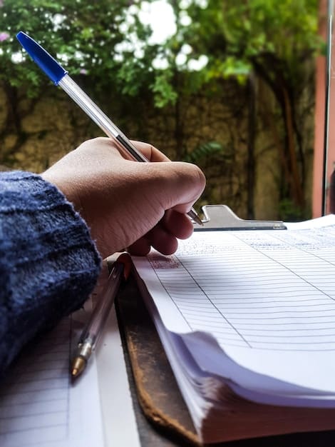 A close-up of a hand carefully filling out a university application form, with a pen poised above the paper. The environment appears organised, with important documents neatly arranged.