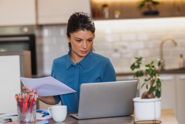 A person completing an online application form for unemployment benefits on their laptop at home, with a stack of documents beside them.